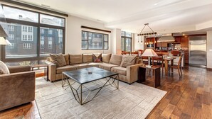 A modern living room with a sectional sofa, a coffee table, and a dining area with chairs and a table.