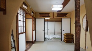 Una habitación japonesa tradicional con suelo de tatami, puertas correderas y una cama con almohadas.