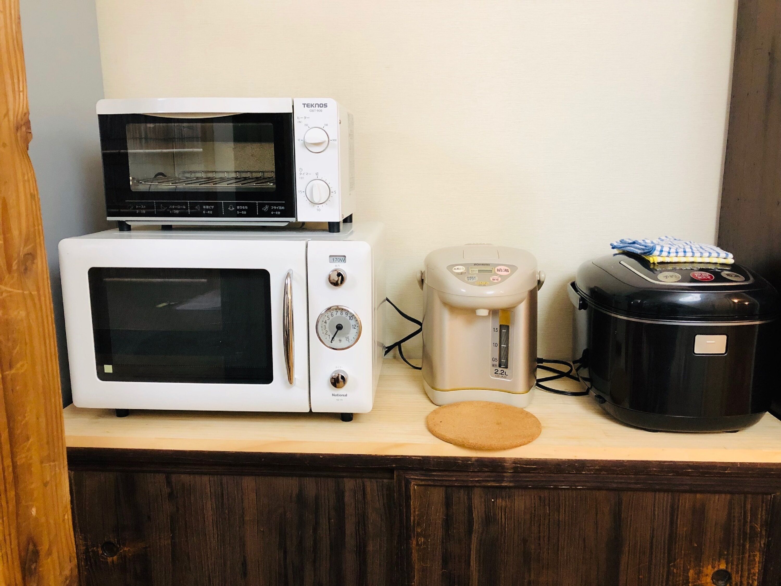 Una cocina con microondas, tostadora y cocedora de arroz sobre una encimera de madera.