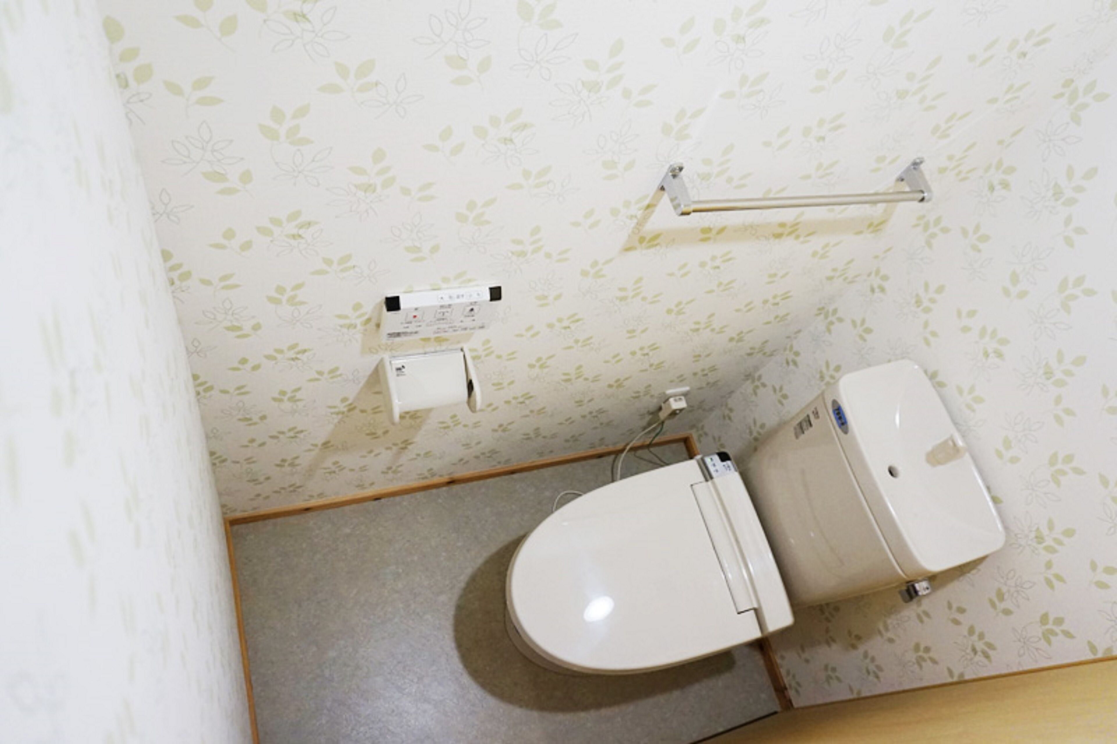 Une salle de bain équipée de toilettes, d’un distributeur d’essuie-tout et d’un sèche-mains fixé au mur.