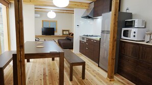 Cocina compacta con suelo de madera, una mesa con bancos y un microondas integrado.