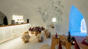 An ice bar with wooden stools and a table set for dining, featuring a unique arctic interior design.