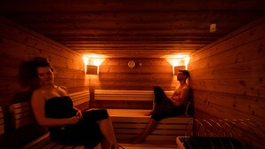A sauna with wooden benches and two people sitting.
