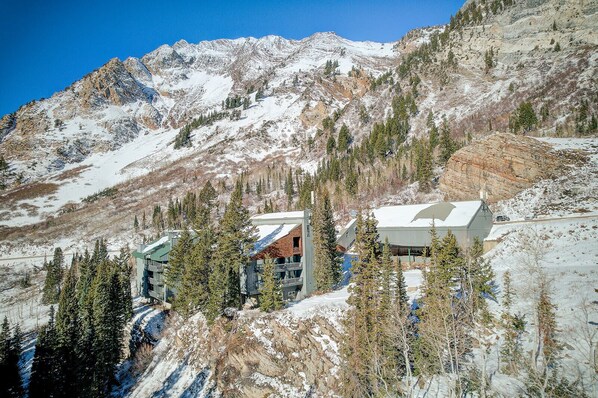 A mountain lodge with multiple buildings, surrounded by snow-covered slopes and evergreen trees.