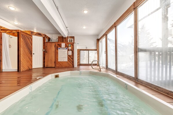 Ein Whirlpool mit Holzboden und großen Fenstern.