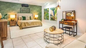 A modern bedroom with a bed, bedside tables, a round coffee table, and artwork on the walls. - Rooftop Penthouse (Key West)