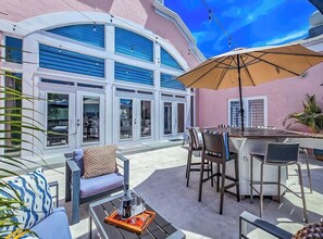 An outdoor patio with a bar area, seating, and a large umbrella. - Rooftop Penthouse (Key West)