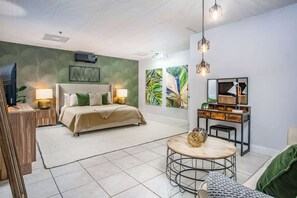 A modern bedroom with a bed, bedside tables, a round coffee table, and artwork on the walls. - Rooftop Penthouse (Key West)