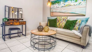 A modern living room with a sofa, a round coffee table, a side table, and a painting on the wall. - Rooftop Penthouse (Key West)