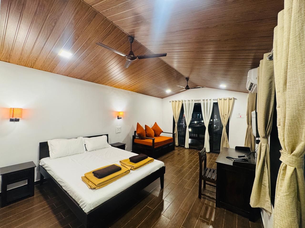 A hotel room with a bed, a desk, a chair, and a sofa.