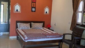 A bedroom with a wooden bed, a ceiling fan, and a wall-mounted light fixture. - Mango Tree Farm (Karjat)