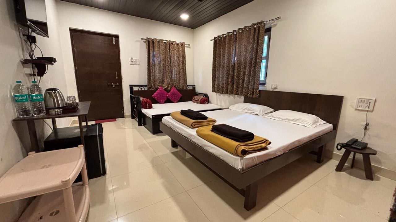 Ein Hotelzimmer mit zwei Betten, einem Schreibtisch, einem Stuhl und einem kleinen Tisch.