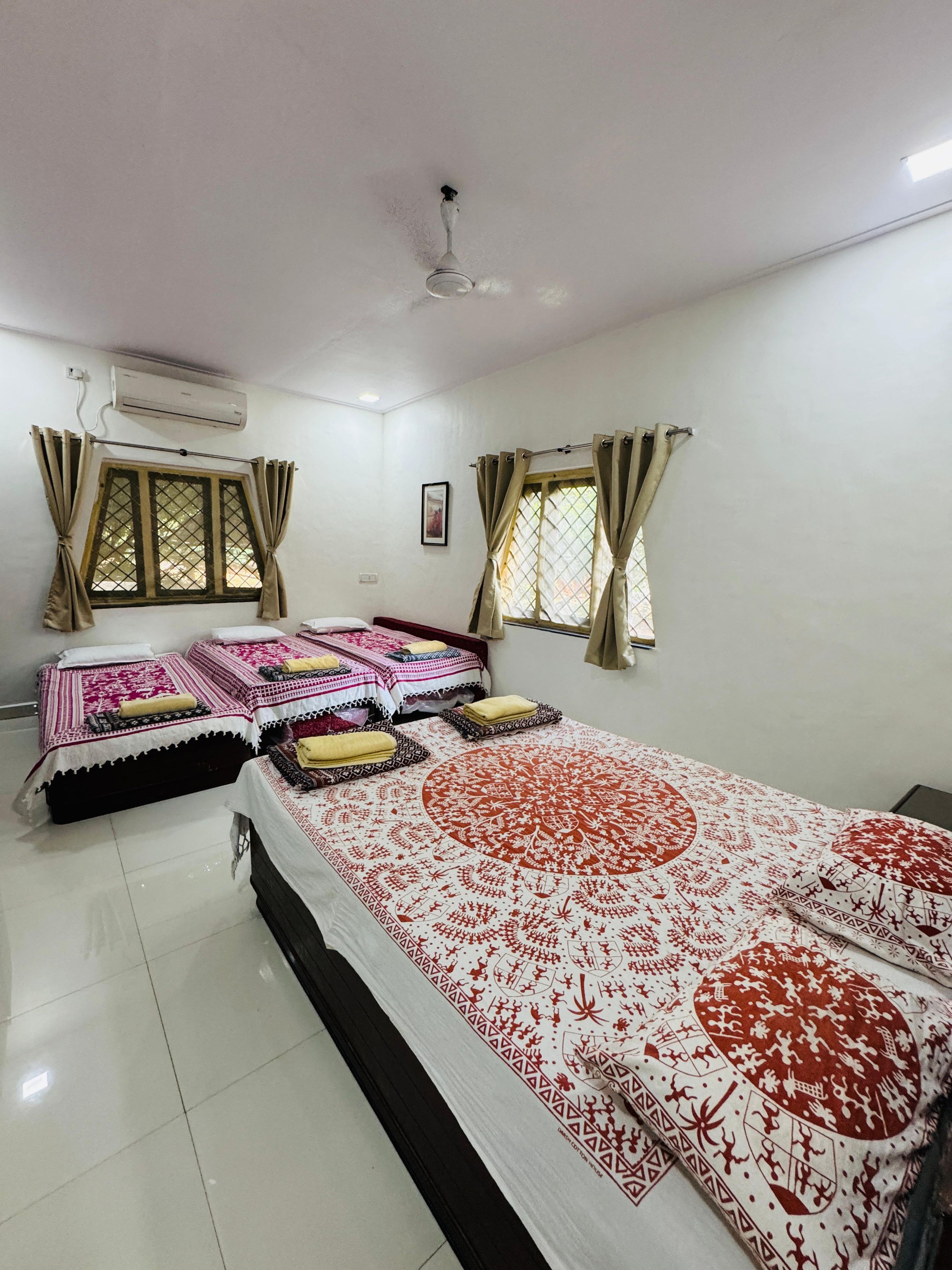 A bedroom with two beds, a ceiling fan, and an air conditioning unit.