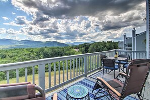 A deck with a view of mountains, a table, chairs, and a railing. - Intervale Family Retreat: Mtn View & Pool Access! (Intervale)