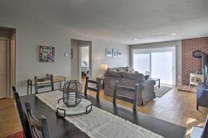 A modern living room with a dining area, featuring a dark wooden table, chairs, and a sofa. - Intervale Family Retreat: Mtn View & Pool Access! (Intervale)