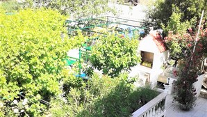A terrace with white lounge chairs, a white balustrade, and lush greenery. - Ferienwohnung Marjetka (Rab)