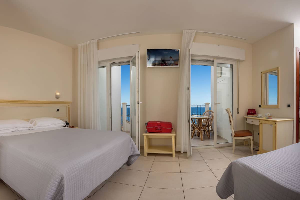 Una habitación de hotel con una cama grande, un escritorio, una silla y un balcón con vistas.
