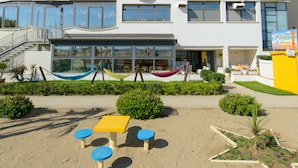 Un hotel de varios pisos con un patio central, mobiliario exterior y una escalera que lleva a la entrada.