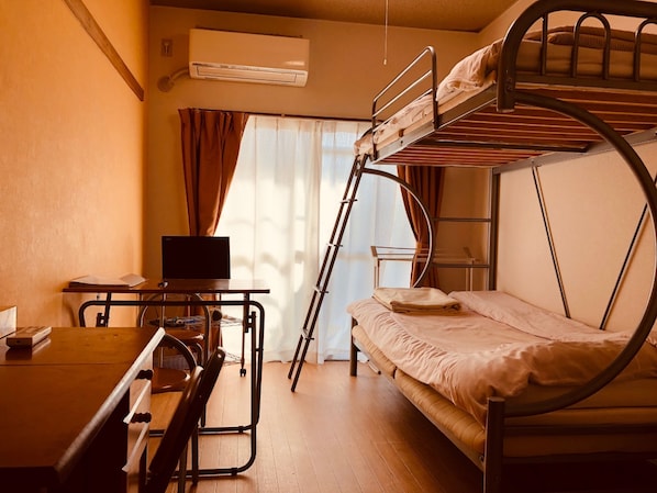 A bunk bed room with a desk, a TV, and an air conditioning unit.