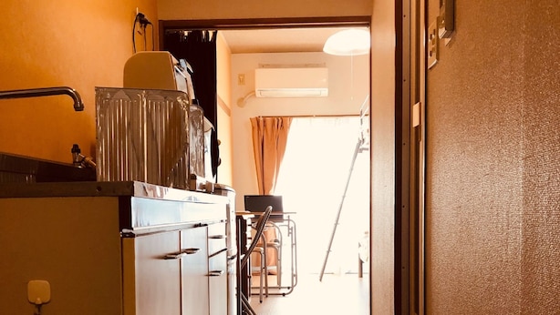 A narrow hallway with a tiled floor leading to a door at the end. There are two pairs of green slippers on the floor. - Nishijin-IVY Bunk bed twin (Kyoto)