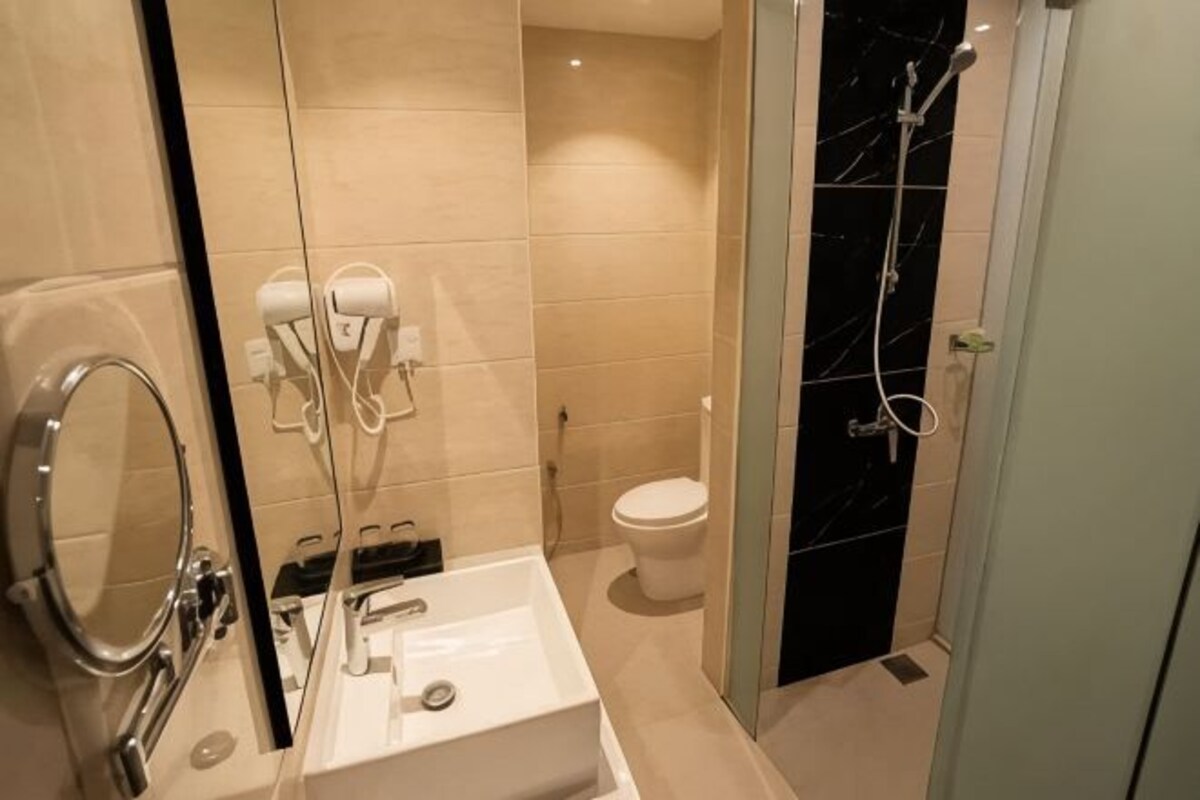 A bathroom with a white sink, a mirror, a toilet, and a shower area.