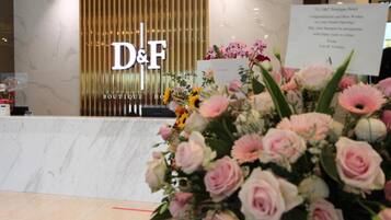A reception desk with a D&F Boutique Hotel sign, a marble counter, and a floral arrangement.