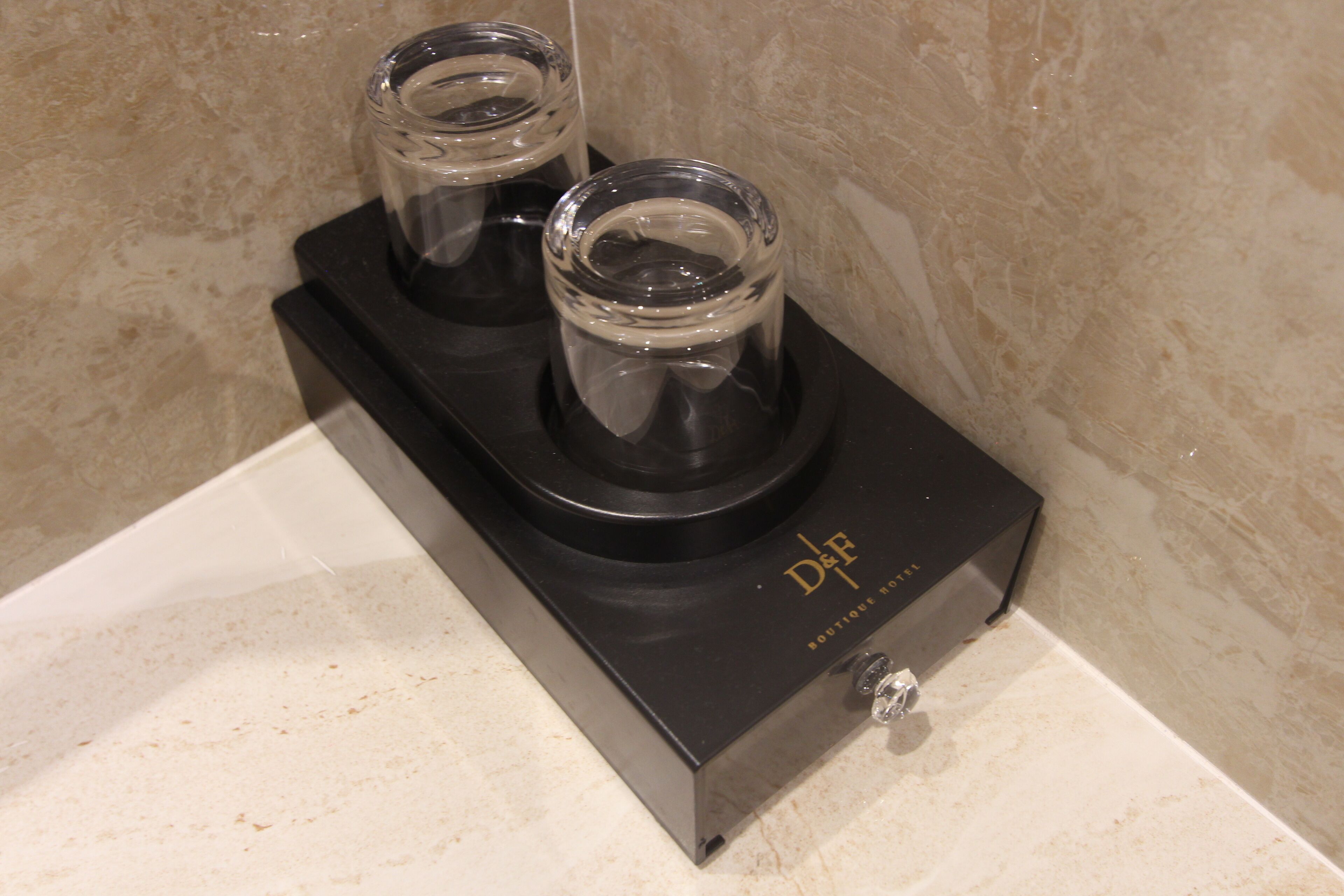A black electronic device with two glass containers on top, placed on a white countertop.