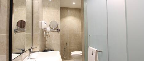 A modern bathroom with a large mirror, a sink, a toilet, and a shower.