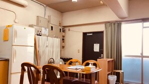 A compact kitchen with a refrigerator, cabinets, and a dining table with chairs. - Nishijin-IVY 5 beds (Kyoto)