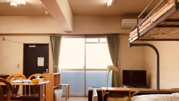 A hotel room with a bunk bed, a desk with a chair, a lamp, a television, and a view of the sea through the window. - Nishijin-IVY 5 beds (Kyoto)