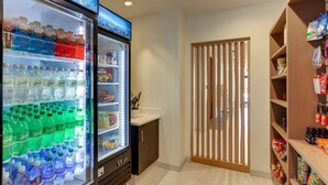 A hotel room with a minibar, a refrigerator stocked with beverages, and a wooden partition. - Holiday Inn Express Wilmington Porters Neck by IHG (Wilmington)