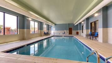 Una piscina interior con agua cristalina azul, rodeada de paredes en una paleta de colores azul claro y blanco.
