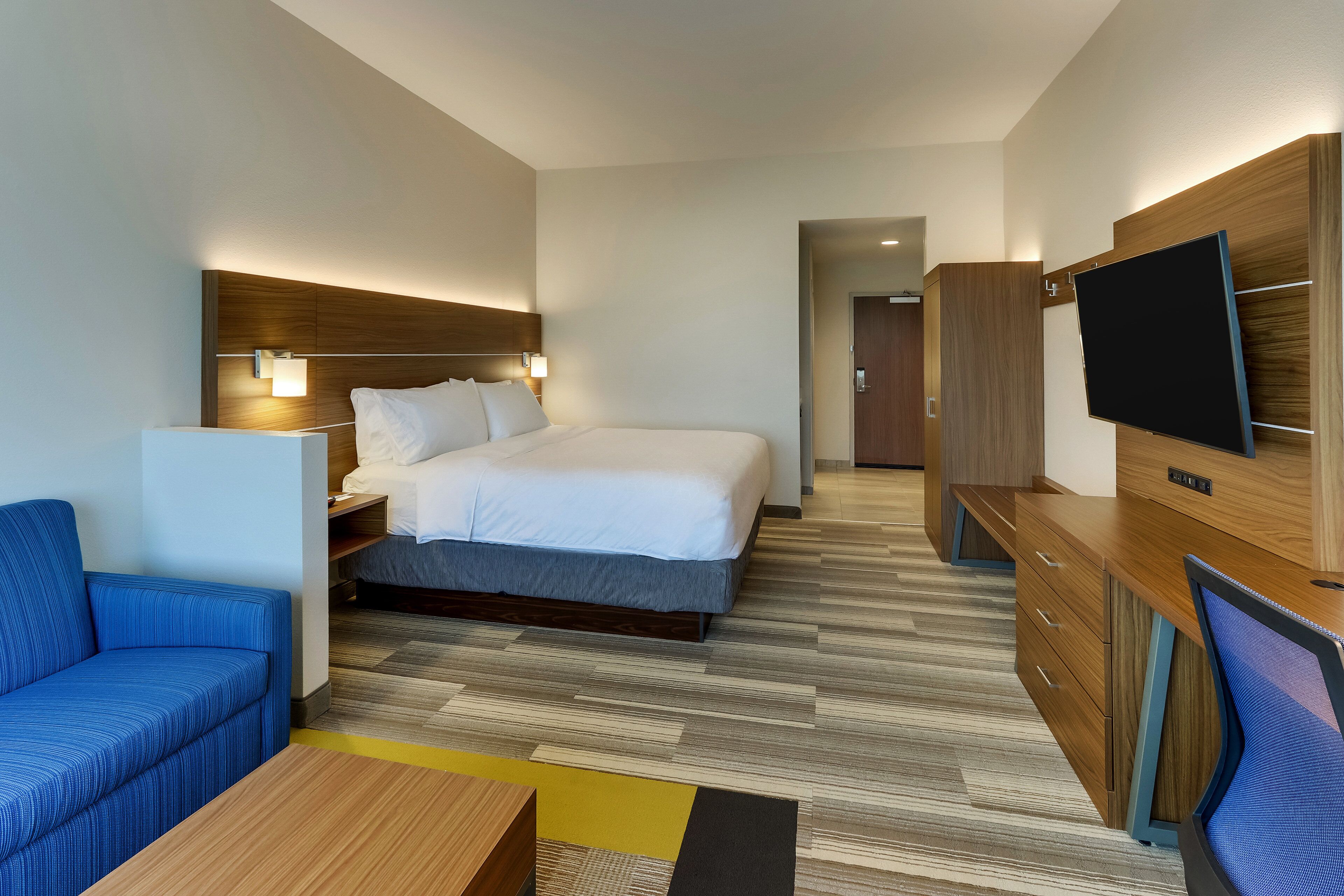 Een hotelkamer met een bed, een bureau, een televisie, een bank en een nachtkastje.