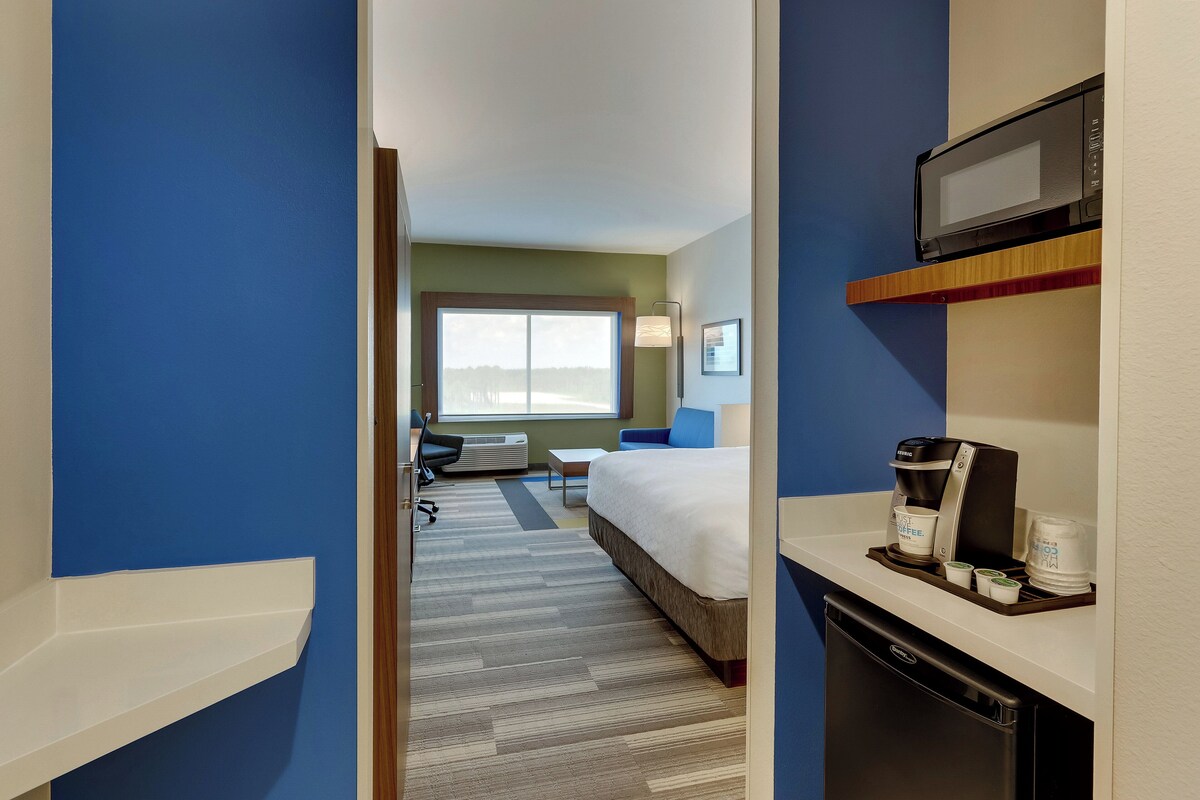 Una habitación de hotel con cama, escritorio, microondas y cafetera.