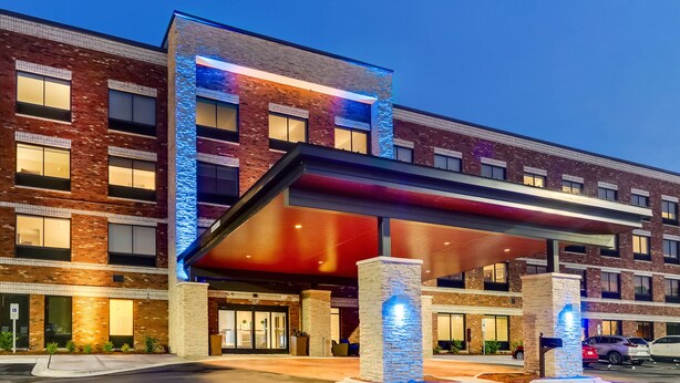 A modern hotel with a brick facade, large windows, and a covered entrance area. - Holiday Inn Express Wilmington Porters Neck by IHG (Wilmington)