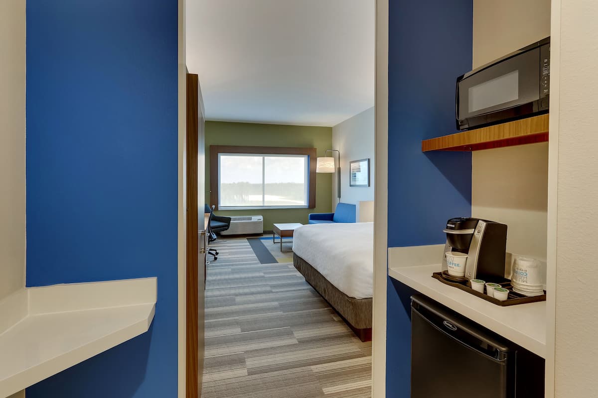 A hotel room with a bed, a desk, a microwave, and a coffee maker.