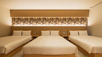 A hotel room with two single beds, a large bed, a wooden headboard, and a patterned wall decoration.