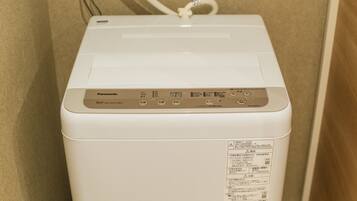 Een witte Panasonic wasmachine met een bedieningspaneel en een etiket aan de zijkant.