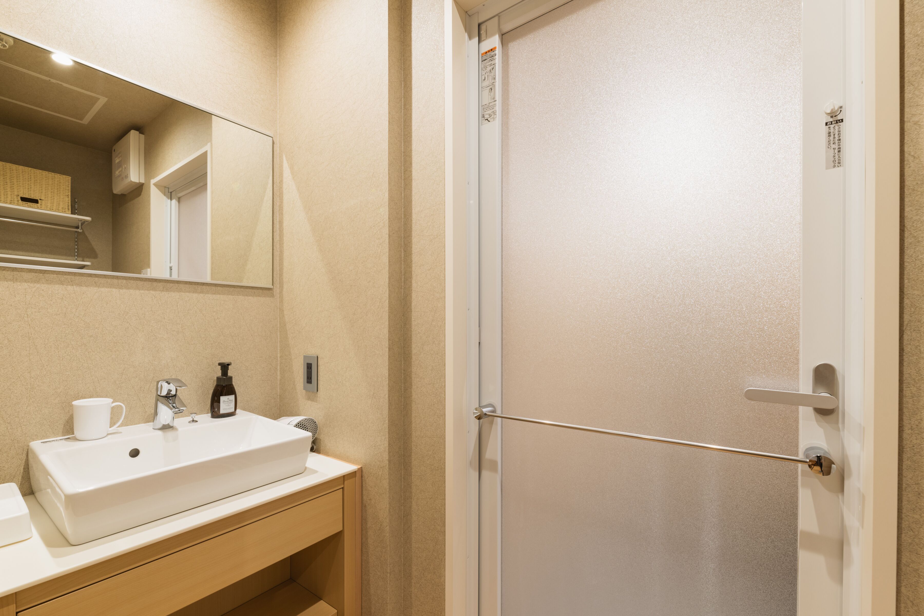 A bathroom with a white sink, a mirror, and a door.