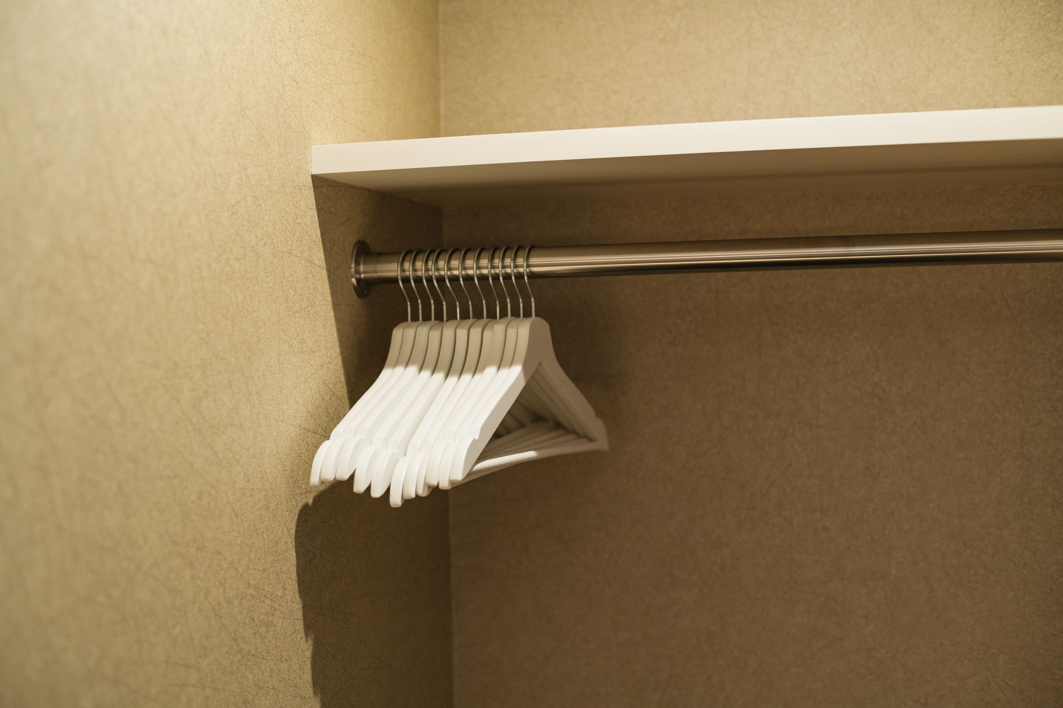 A white towel rack with multiple towels hanging on it, mounted on a beige wall.
