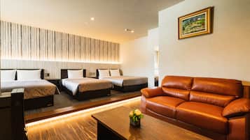 Habitación de hotel con sofá, dos camas, una mesita de madera y un cuadro colgado en la pared.