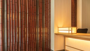 A reception area with a wooden panel wall and a reception desk with a lighted panel. - GRAND BASE Hakatamon (Fukuoka)