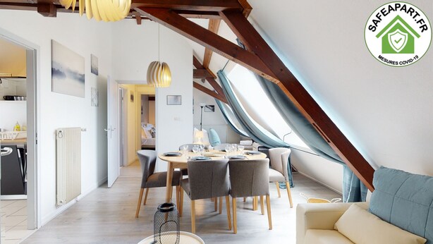Ein modernes Loft-Zimmer mit Essbereich, einer Couch und Blick durch ein Dachfenster.