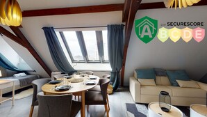 Ein Essbereich mit einem runden Tisch für vier Personen, einer Couch und einem Fenster mit Vorhängen.