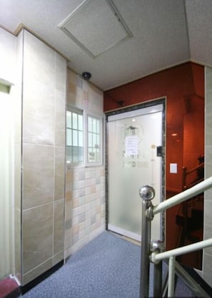 Corridors feature a tiled floor and walls, with a metal handrail and a window.