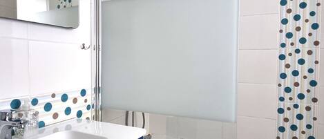 Une salle de bain avec des carreaux blancs, un lavabo bleu et une douche avec une porte en verre.