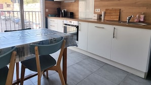 Een moderne keuken met witte kasten, een magnetron en een houten aanrecht.