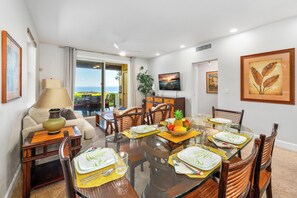A dining area with a glass table, chairs, and a view of the ocean. - Ocean Front With Stunning Views! Halii Kai 13E (Waikoloa Village)