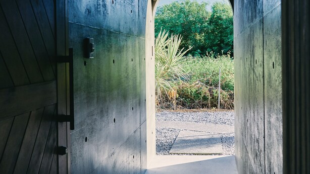 A concrete corridor with a circular opening leading to a garden area. - IMAGINE OKINAWA (Nakijin)