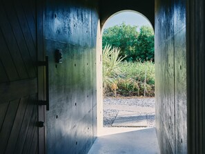 A concrete corridor with a circular opening leading to a garden area. - IMAGINE OKINAWA (Nakijin)